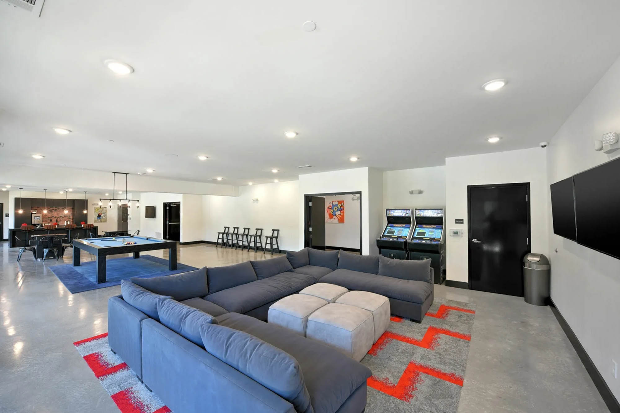 Comfortable couches and games room with mounted TV pool table and arcade games